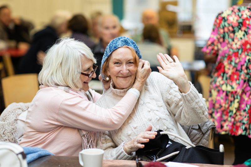 Two older women laughing together in a cafe