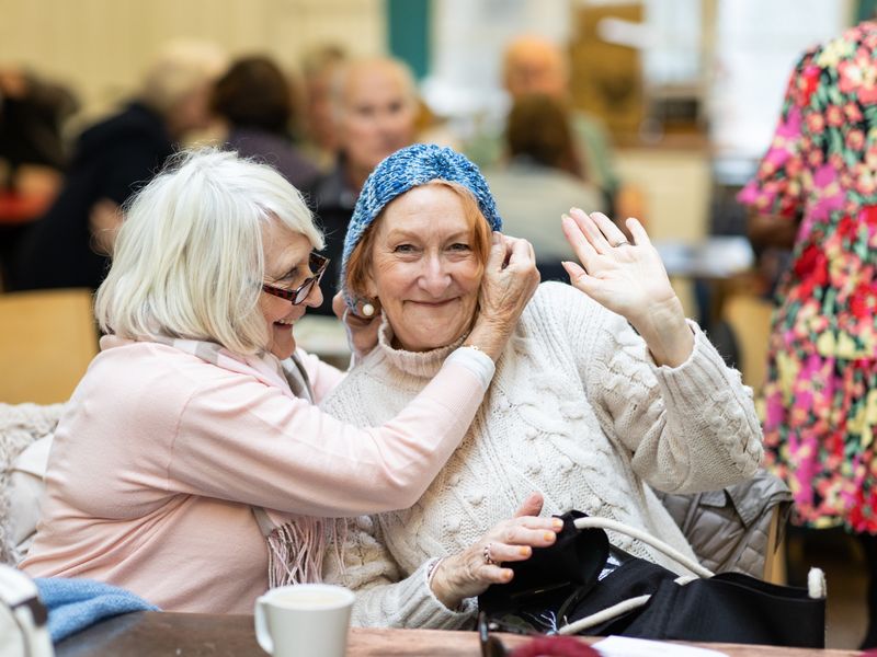 Two older women laughing together in a cafe