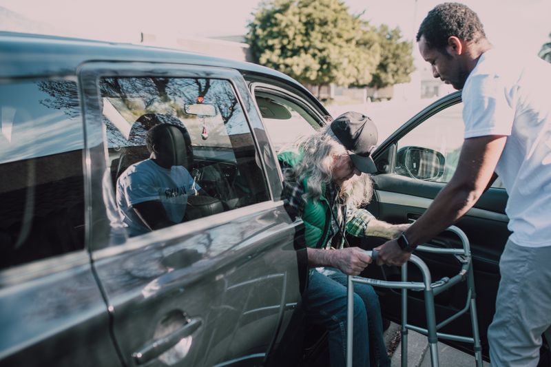 An older man being helped into a car