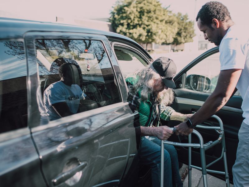 An older man being helped into a car