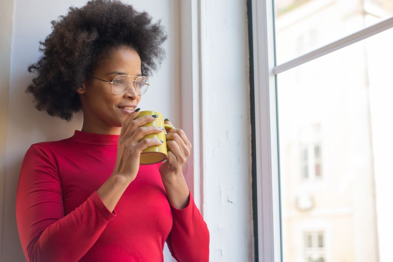 A woman enjoying a quiet moment with a hot drink by the window