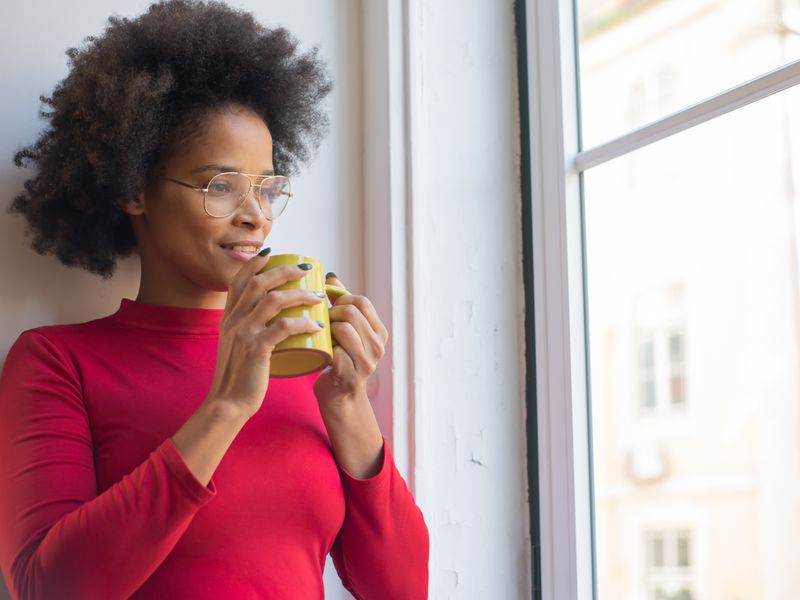 A woman enjoying a quiet moment with a hot drink by the window