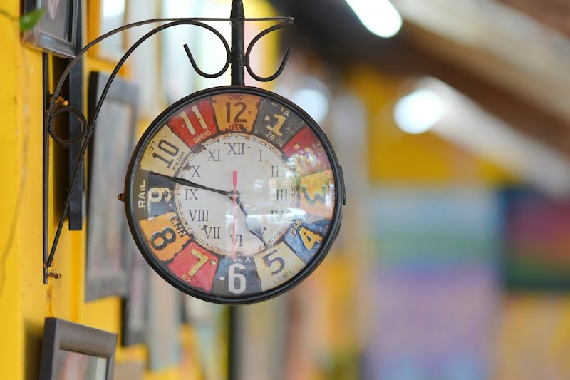 A colourful clock on a sunny yellow wall