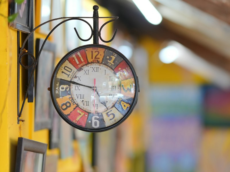 A colourful clock on a sunny yellow wall