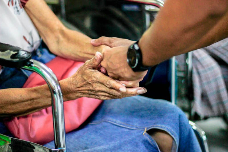 Holding an older person's hands in reassurance