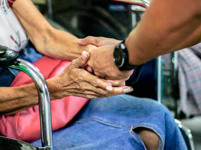 Holding an older person's hands in reassurance