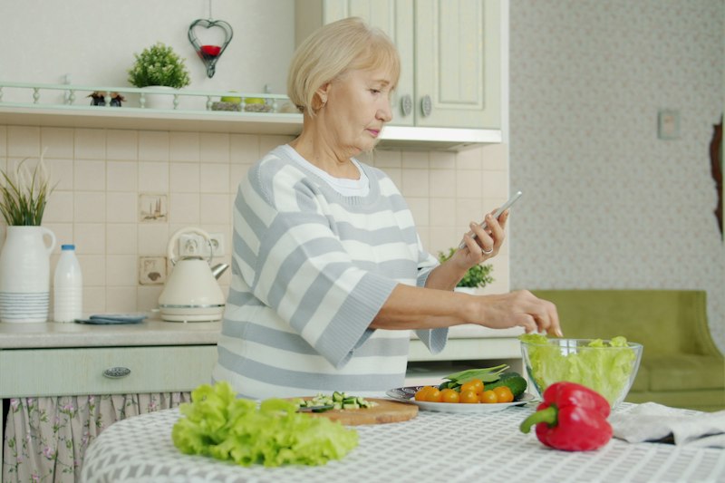 An older woman preparing a fresh salad in her kitchen