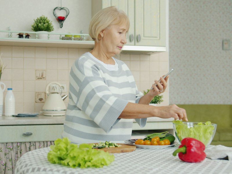 An older woman preparing a fresh salad in her kitchen