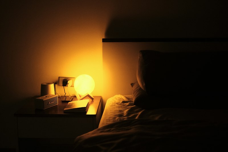 A bedside lamp glowing softly in a bedroom at night