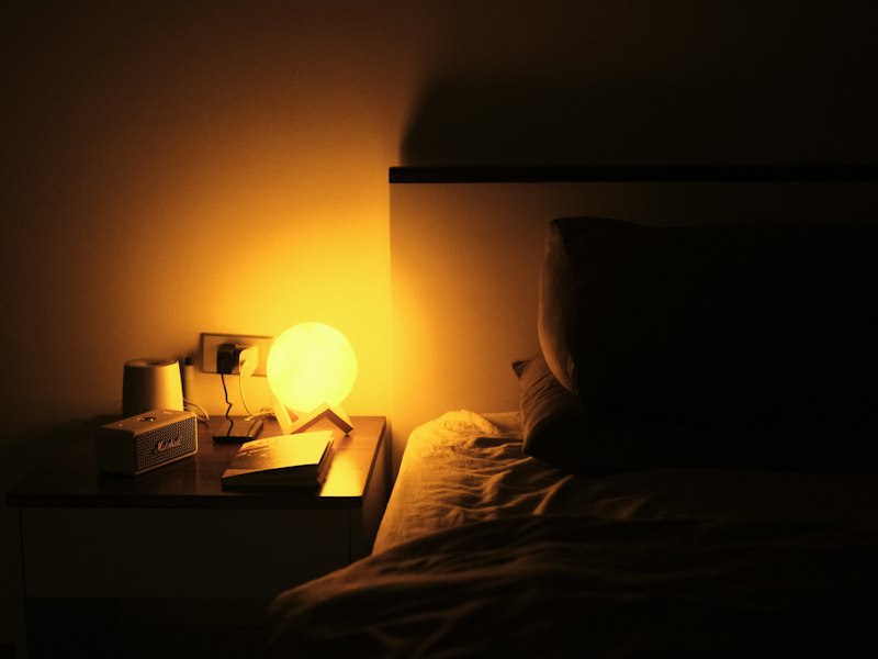 A bedside lamp glowing softly in a bedroom at night