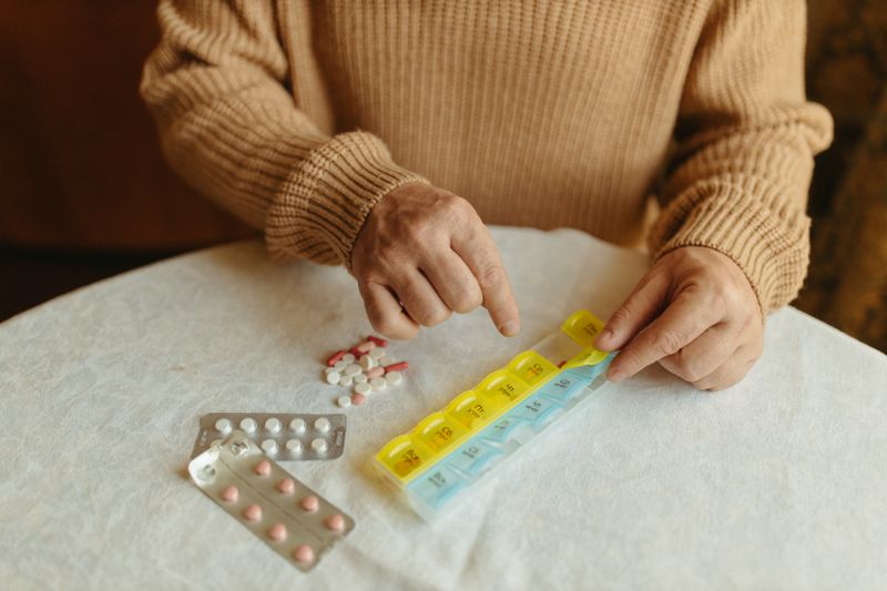 An older person sorting their own tablets into a weekly pill organiser