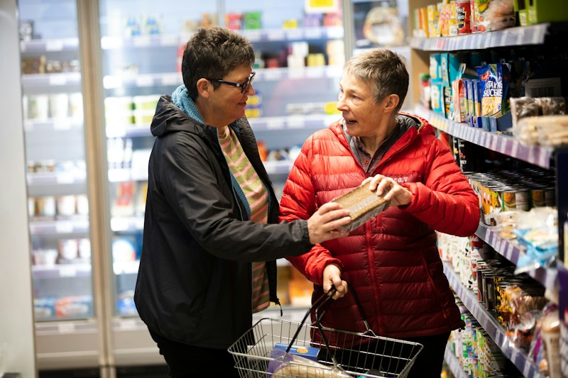 Two women laughing together while doing the food shopping