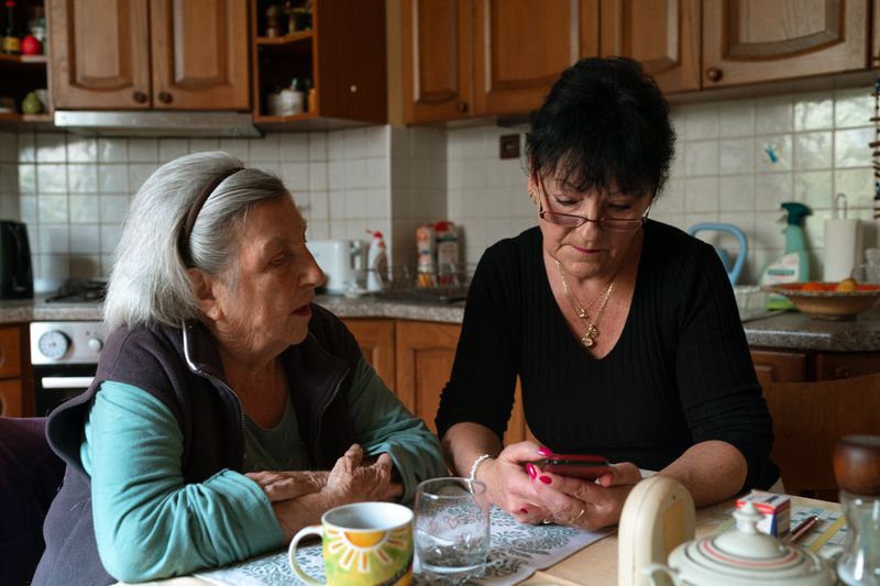 An older woman and a carer spending time together at the kitchen table