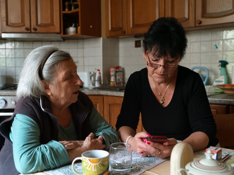 An older woman and a carer spending time together at the kitchen table